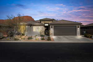 Prairie-style house featuring stone siding, concrete driveway, a gate, stucco siding, and a garage