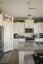 Kitchen featuring dark stone counters, recessed lighting, white cabinets, decorative backsplash, and stainless steel appliances