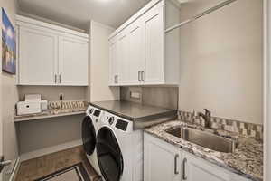 Laundry room with dark wood finished floors, separate washer and dryer, and cabinet space