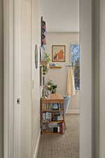 Corridor featuring light colored carpet and baseboards
