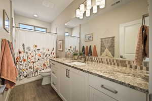 Full bath featuring vanity, dark wood-style floors, and shower / bath combination with curtain