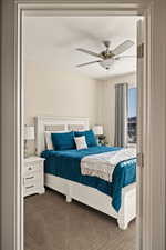 Bedroom with dark colored carpet and a ceiling fan