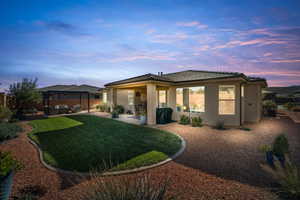 Back of house at dusk featuring a patio, stucco siding, and a tile roof