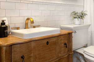 Half bath with vanity and tasteful backsplash