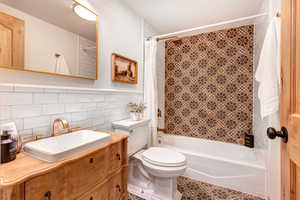 Bathroom featuring shower / bath combination with curtain, vanity, and tile walls