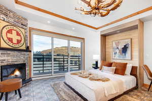 Bedroom featuring a raised ceiling, a brick fireplace, access to exterior, ornamental molding, and recessed lighting