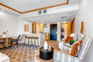 Living area with recessed lighting, estacked washer and dryer, and ornamental molding