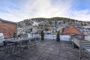 Snow covered patio with a patio, a mountain view, outdoor dining area, and grilling area