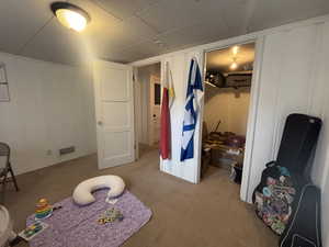Recreation room with light colored carpet and a decorative wall