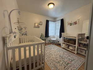Bedroom featuring a crib and wood finished floors