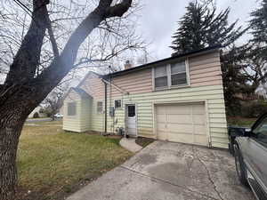View of front of property with a front yard, a garage, a chimney, and driveway