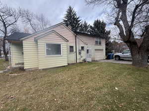 Rear view of property with asphalt driveway, a lawn, and an attached garage