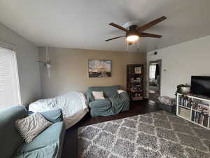 Living room featuring dark wood-style flooring and ceiling fan