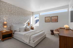 Carpeted bedroom featuring wallpapered walls and an accent wall
