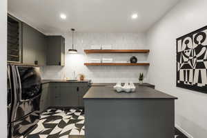 Kitchen featuring dark countertops, open shelves, black fridge, gray cabinetry, and pendant lighting