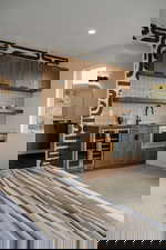 Bar with backsplash, open shelves, wine cooler, brown cabinets, and stainless steel microwave