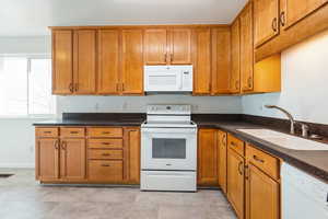 Kitchen with white appliances, brown cabinets, and dark stone counters