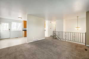 Empty room featuring light colored carpet and a chandelier