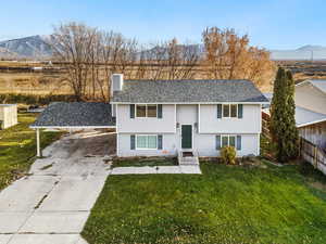 Bi-level home featuring a mountain view, a front yard, a chimney, and driveway
