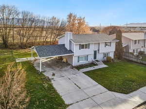 View of front facade with an attached carport, a chimney, concrete driveway, and roof with shingles