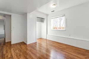 Unfurnished bedroom with wood finished floors and a closet