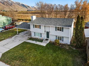Raised ranch featuring a chimney, a front lawn, a mountain view, and roof with shingles