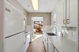 Kitchen featuring decorative backsplash, white appliances, white cabinets, and light stone countertops