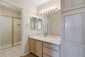 Full bathroom with vanity, a stall shower, and light tile patterned floors