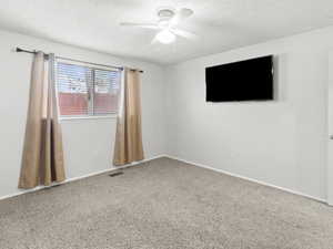 Carpeted spare room with a textured ceiling and a ceiling fan