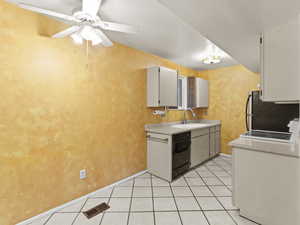 Kitchen with light countertops, electric stove, light tile patterned floors, and dishwasher