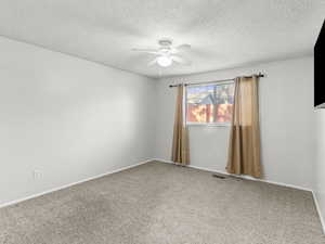 Carpeted spare room with a textured ceiling and ceiling fan