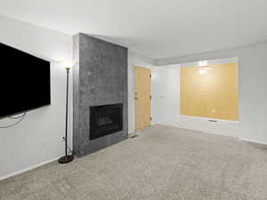 Unfurnished living room with carpet floors, a fireplace, tile patterned floors, and a ceiling fan