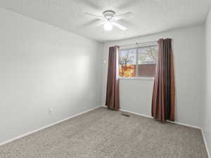 Empty room with carpet, ceiling fan, and a textured ceiling