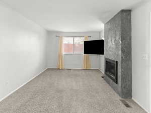Unfurnished living room with a large fireplace and carpet floors
