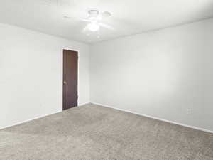Empty room with carpet floors, a textured ceiling, and ceiling fan