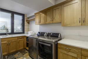 Laundry room featuring washing machine and dryer, dark stone finish floors, and cabinet space