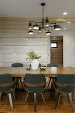 Dining room with hardwood / wood-style flooring, wooden walls, a chandelier, and recessed lighting