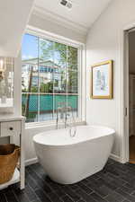 Full bathroom with a freestanding tub and vaulted ceiling