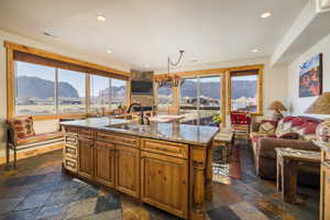 Kitchen featuring brown cabinets, light stone countertops, open floor plan, healthy amount of natural light, and recessed lighting
