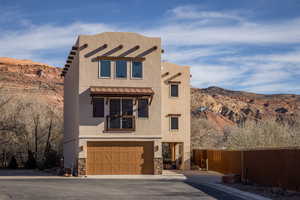 View of front facade featuring a mountain view, stone siding, stucco siding, and a garage