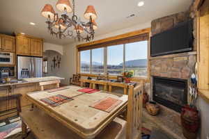 Dining area featuring arched walkways, a fireplace, a chandelier, and recessed lighting