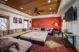 Carpeted living area featuring a raised ceiling, wooden ceiling, a ceiling fan, and recessed lighting