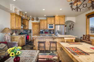 Kitchen featuring arched walkways, recessed lighting, stainless steel appliances, a kitchen bar, and tasteful backsplash