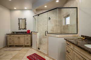 Full bathroom with two vanities, a shower stall, recessed lighting, and light tile patterned flooring