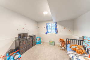 Bedroom featuring light carpet and a crib