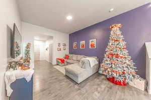 Living area featuring light wood finished floors, an accent wall, and recessed lighting