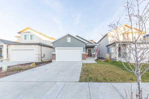 View of front facade featuring stucco siding, driveway, a front yard, a garage, and brick siding