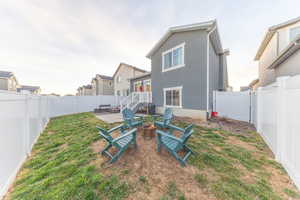 Rear view of house featuring stucco siding, a fenced backyard, a patio area, and an outdoor fire pit
