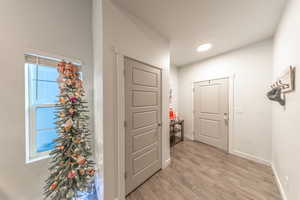 Hallway with light wood finished floors and recessed lighting