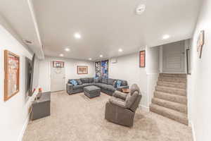 Living room featuring light colored carpet, recessed lighting, and stairway